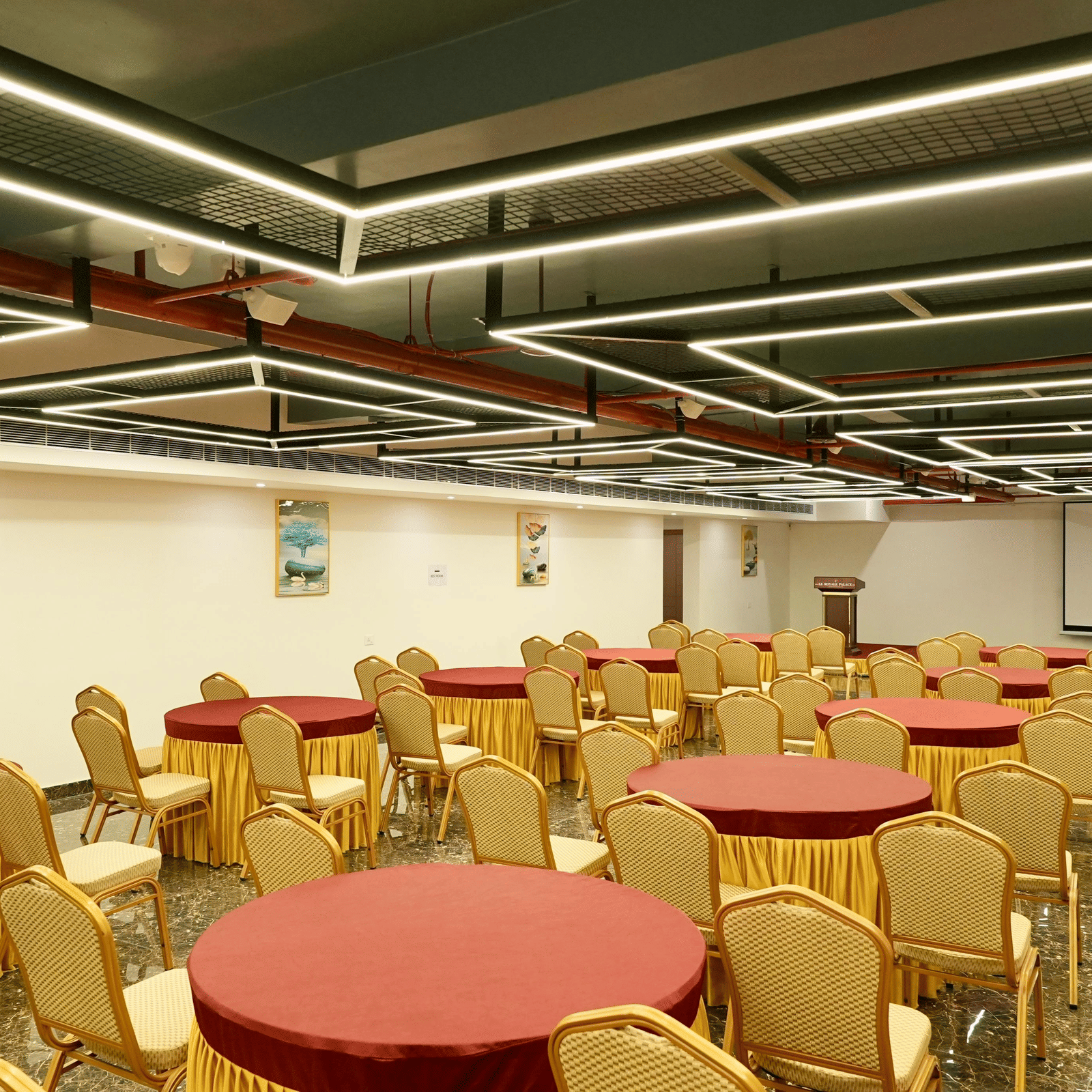 A gathering hall in Le Royale palace with multiple chairs and tables arranged in cluster formation and modern ceiling