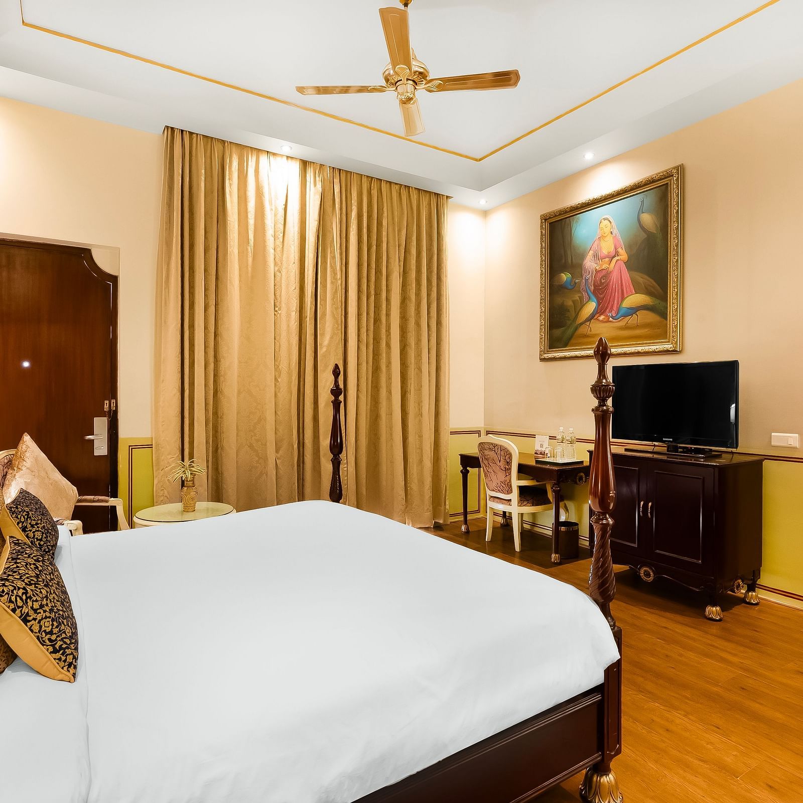 An overview of a room with a double bed, tv and a ceiling fan inside it - Rajasthali Resort & Spa, Jaipur.