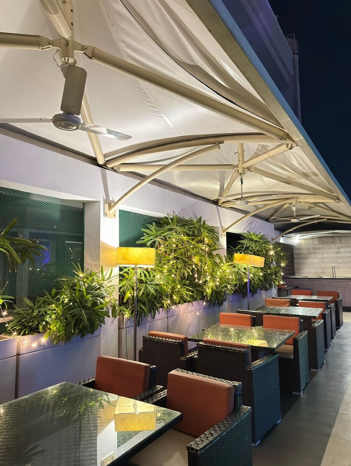 Dining area with tables, chairs, and potted plants at the side of Cenneys Gateway.
