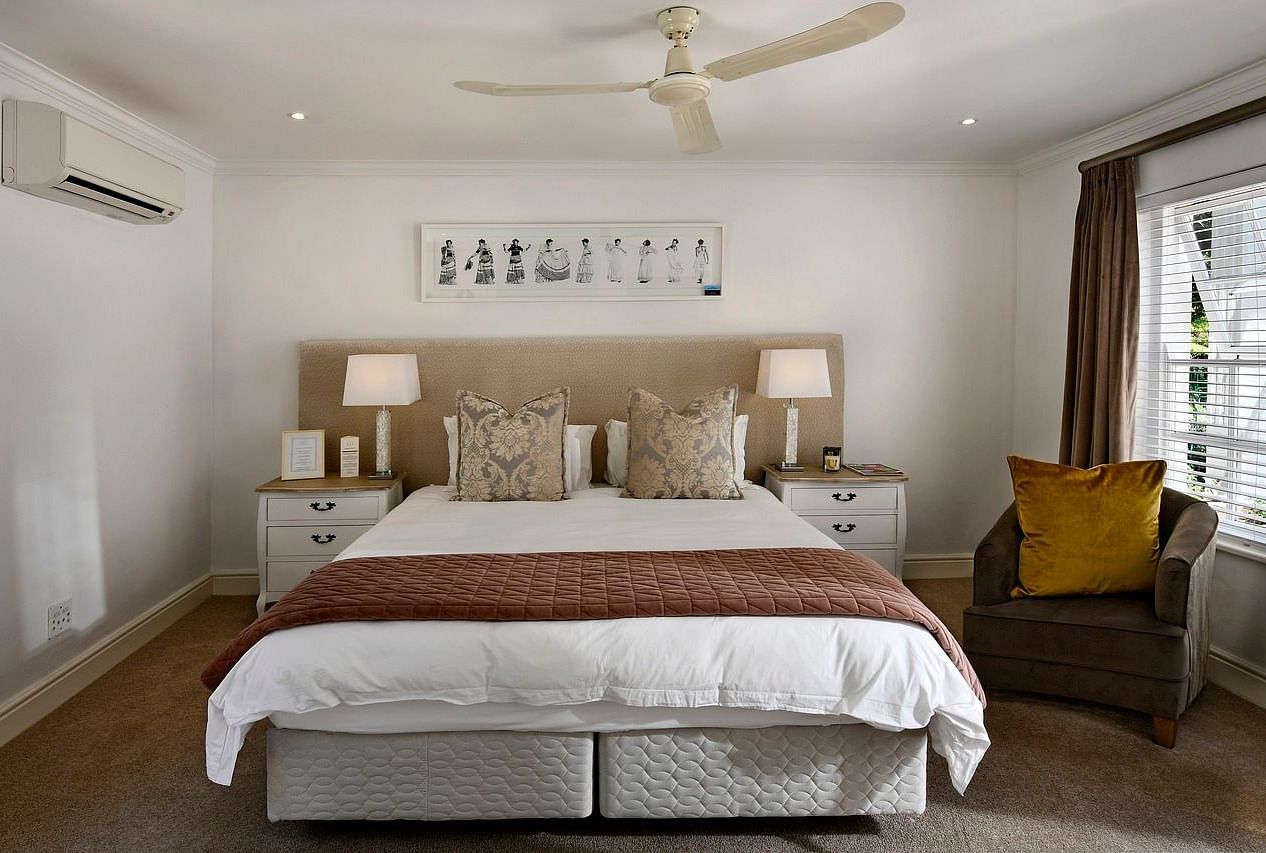 A double bed with a ceiling fan hanging over it in a bedroom.