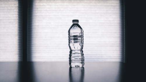 a portrait shot of a filled water bottle kept on a table.