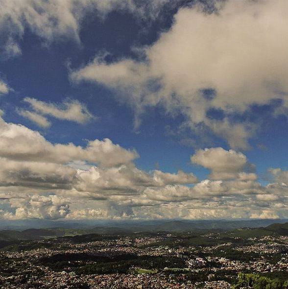 A sweeping view of the Shillong city skyline from above, with a dramatic, cloudy sky, near the Polo Hotel Shillong.