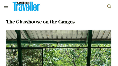 Breakfast table for two by floor-to-ceiling glass windows overlooking lush forest and a river below.