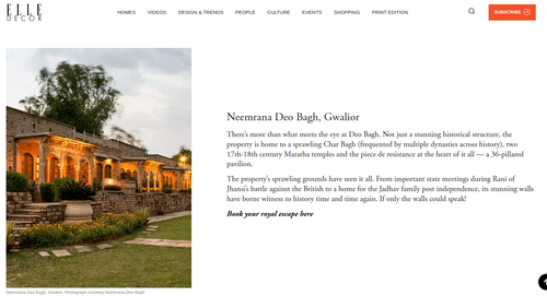 Article on Elle Decor featuring Neemrana Deo Bagh in Gwalior illuminated at twilight, showcasing grand stone architecture, vibrant gardens, and rich historical elegance.