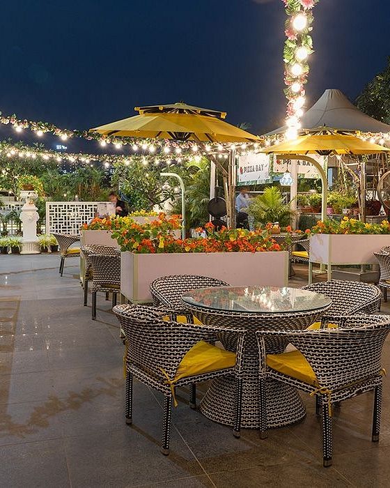 Outdoor dining space at Karma Chalets with round tables, string lights, and yellow umbrellas set up in the evening.