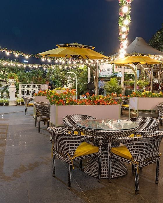 Outdoor dining space at Karma Chalets with round tables, string lights, and yellow umbrellas set up in the evening.