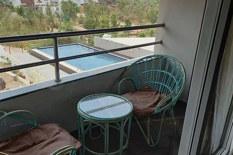 Cosy balcony with seating, overlooking greenery, suggesting a peaceful retreat.