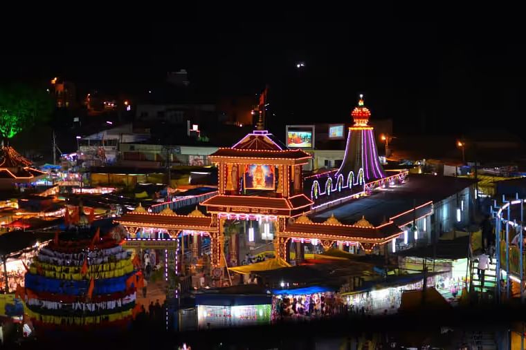 A beautifully illuminated temple complex at night, with surrounding structures lit up.