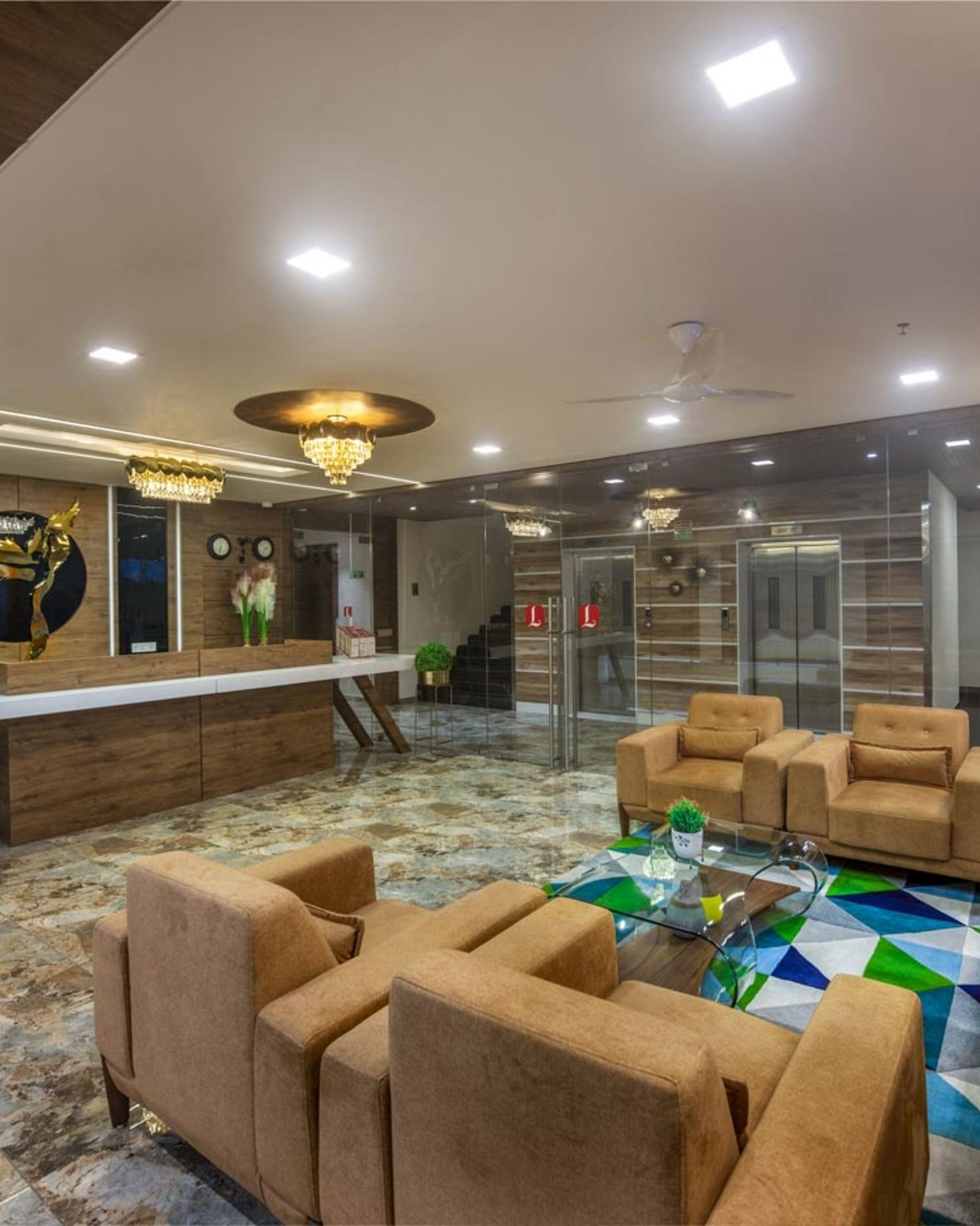 A spacious hotel lobby area with comfortable seating arrangements, tables, and decorative lighting at Angel Lords Eco Inn Amreli.