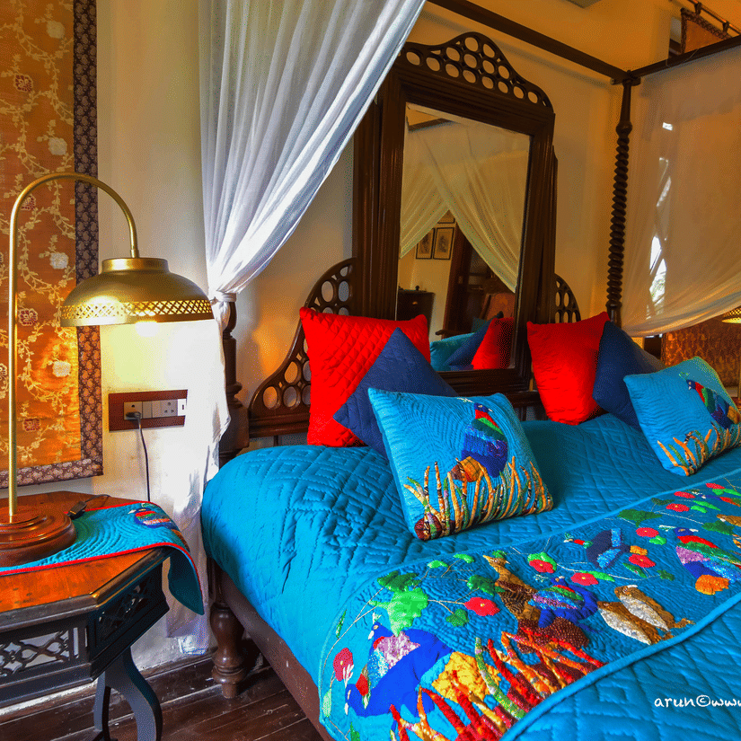 Vintage bedroom with a four-poster bed and colorful decor at a riverside resort in Dehradun.