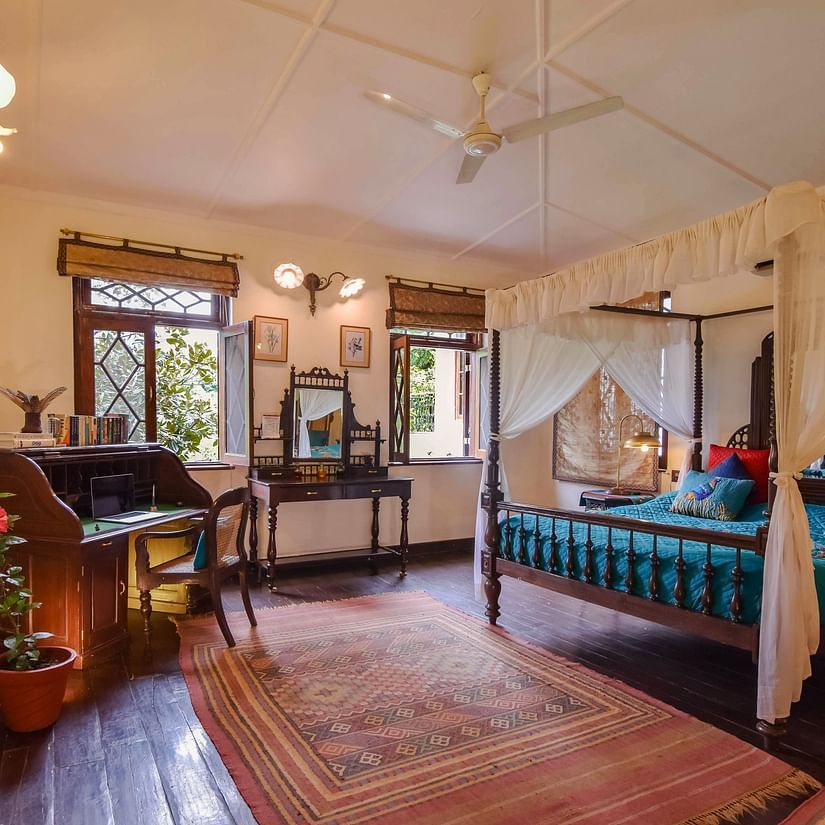 A spacious bedroom with a four-poster bed and a view of the outdoors.