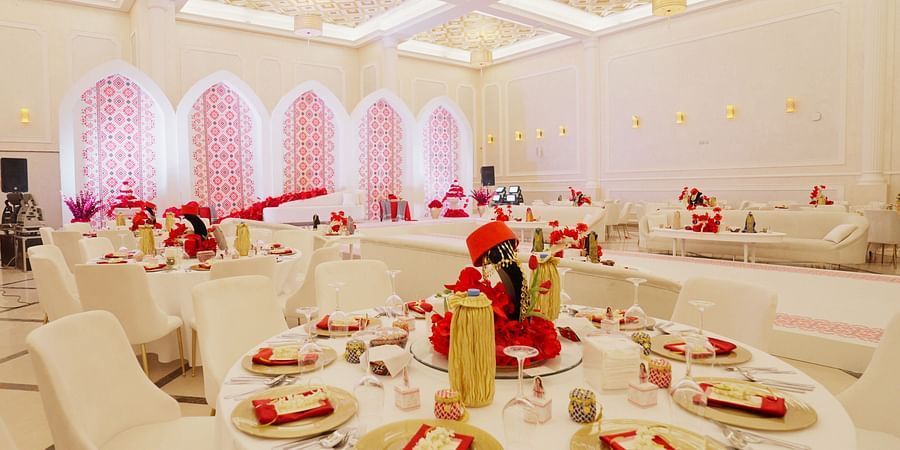 An elegantly decorated banquet hall at La Maison, Doha, with round tables set for a formal event.