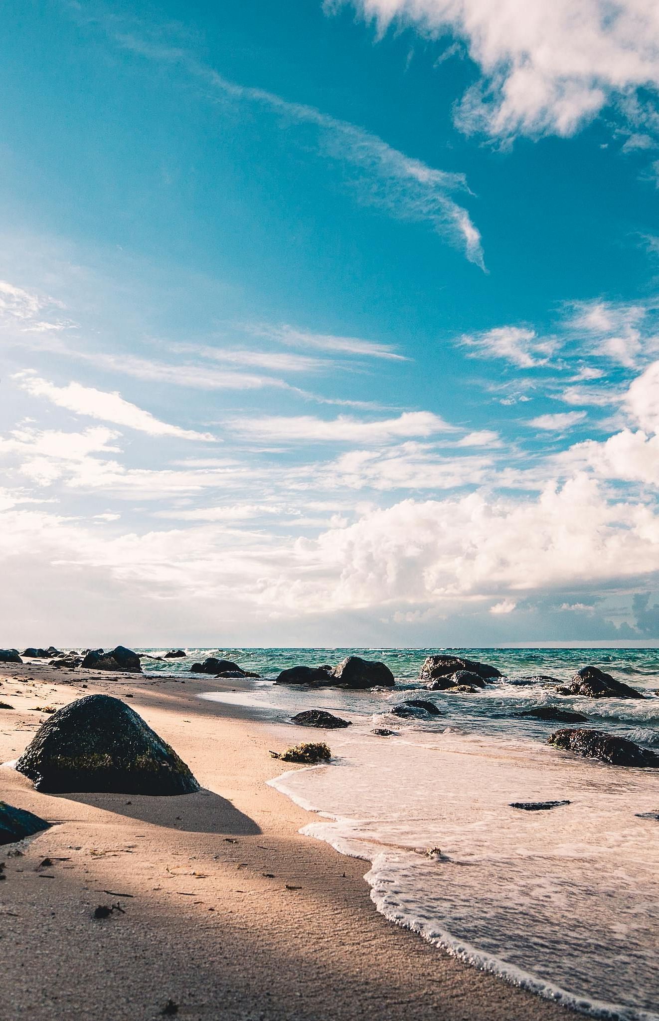 Beach view with gentle, pleasant waves and a partially cloudy sky