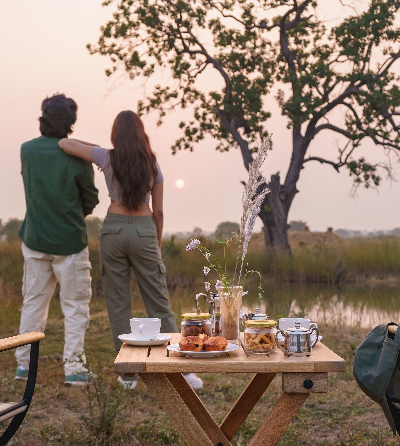 Couple watching a sunset with a dining setup at Trees N Tigers, Tadoba.