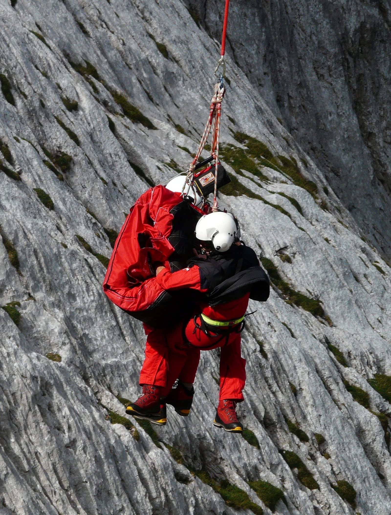 image featuring a two people dressed in red coloured protective jerseys coming down from a mountain cliff