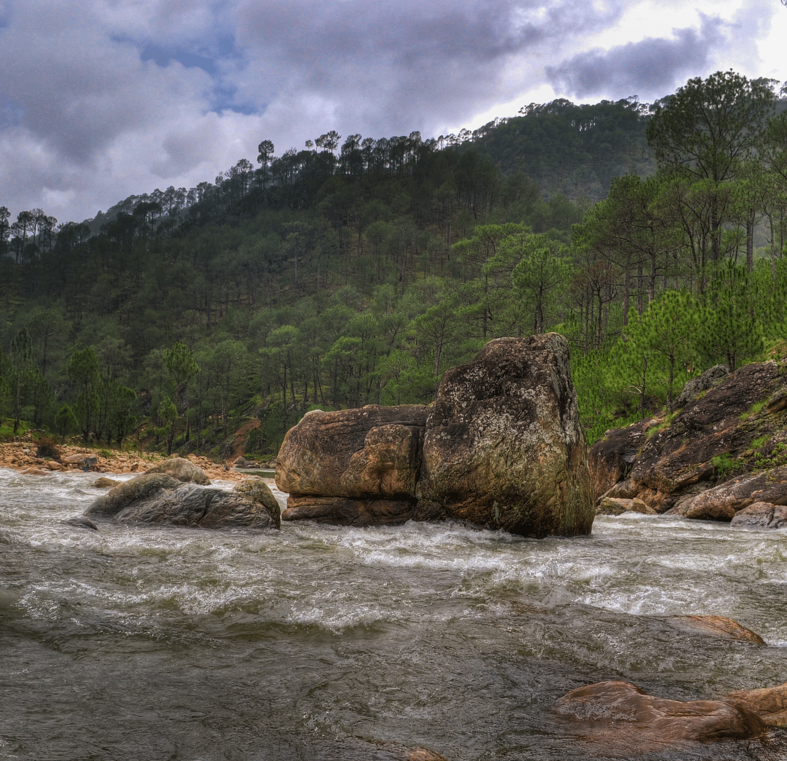An image of a stream filled with stones and a mountain at the distance