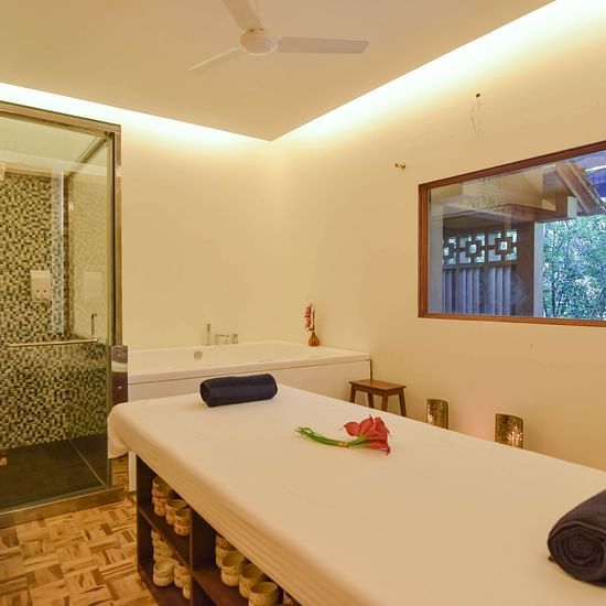 A serene spa room with a massage table and shower.
