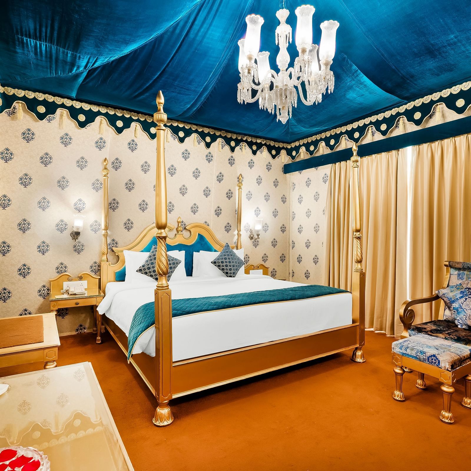 An overview of a tent with a double bed, a chair and a table inside it - Rajasthali Resort & Spa, Jaipur.