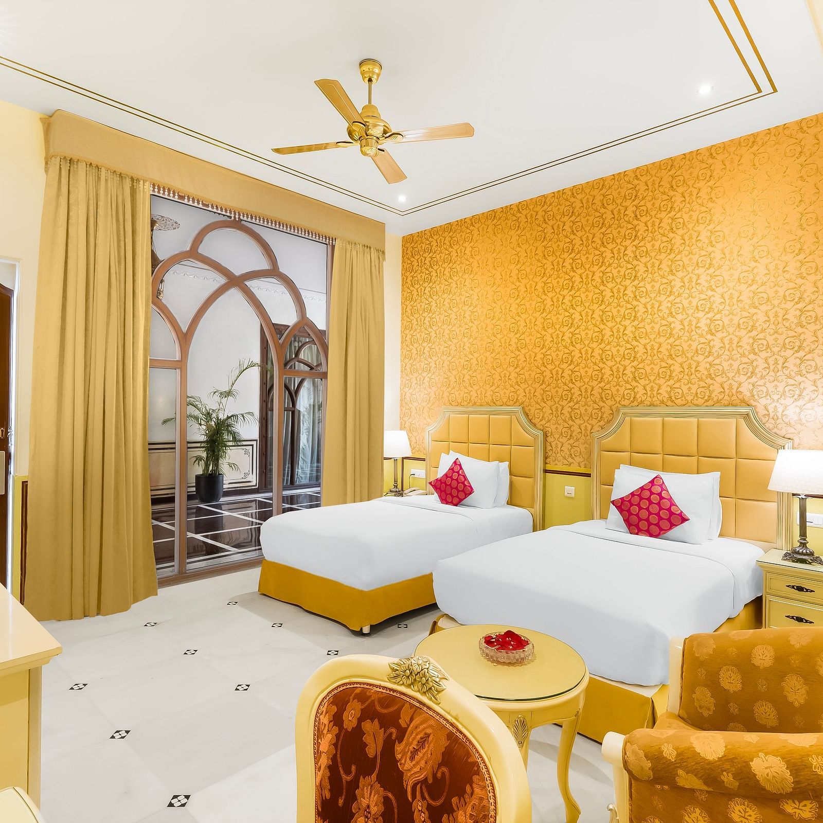 An overview of a room with two single beds, a chair and ceiling fan in view - Rajasthali Resort & Spa, Jaipur.