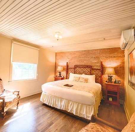 full view image of a bedroom featuring a bricked wall behind the double bed - Historic Tapoco Lodge