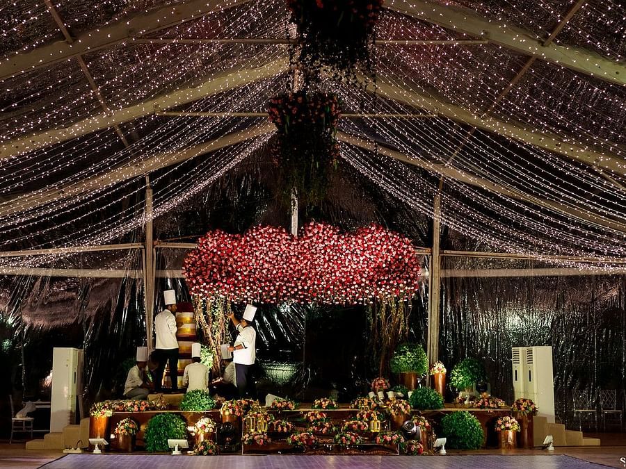 Indoor event space with beautiful ceiling decorations of hanging floral arrangements, draped lights, and elegant floral centrepieces at Black Thunder, Coimbatore