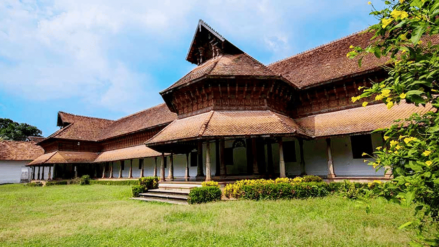 A traditional wooden-roofed structure with multiple sloping roofs set amid green trees.