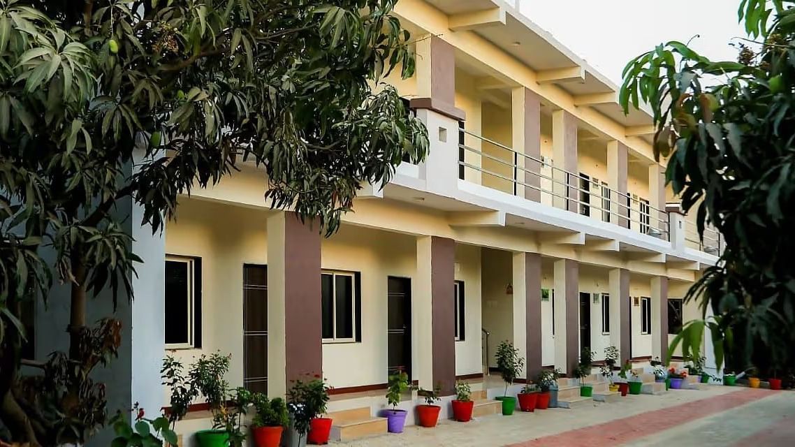 Facade of Daksh Resort & Amusement Part featuring a two-storey building with a row of rooms, plants, and a paved path .