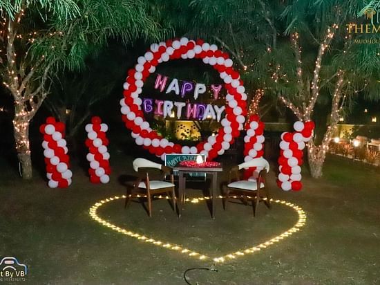 An image of a lawn decorated with balloons and happy birthday banners at Themis Mudhouse - A Nature's Retreat Resort & Wellness