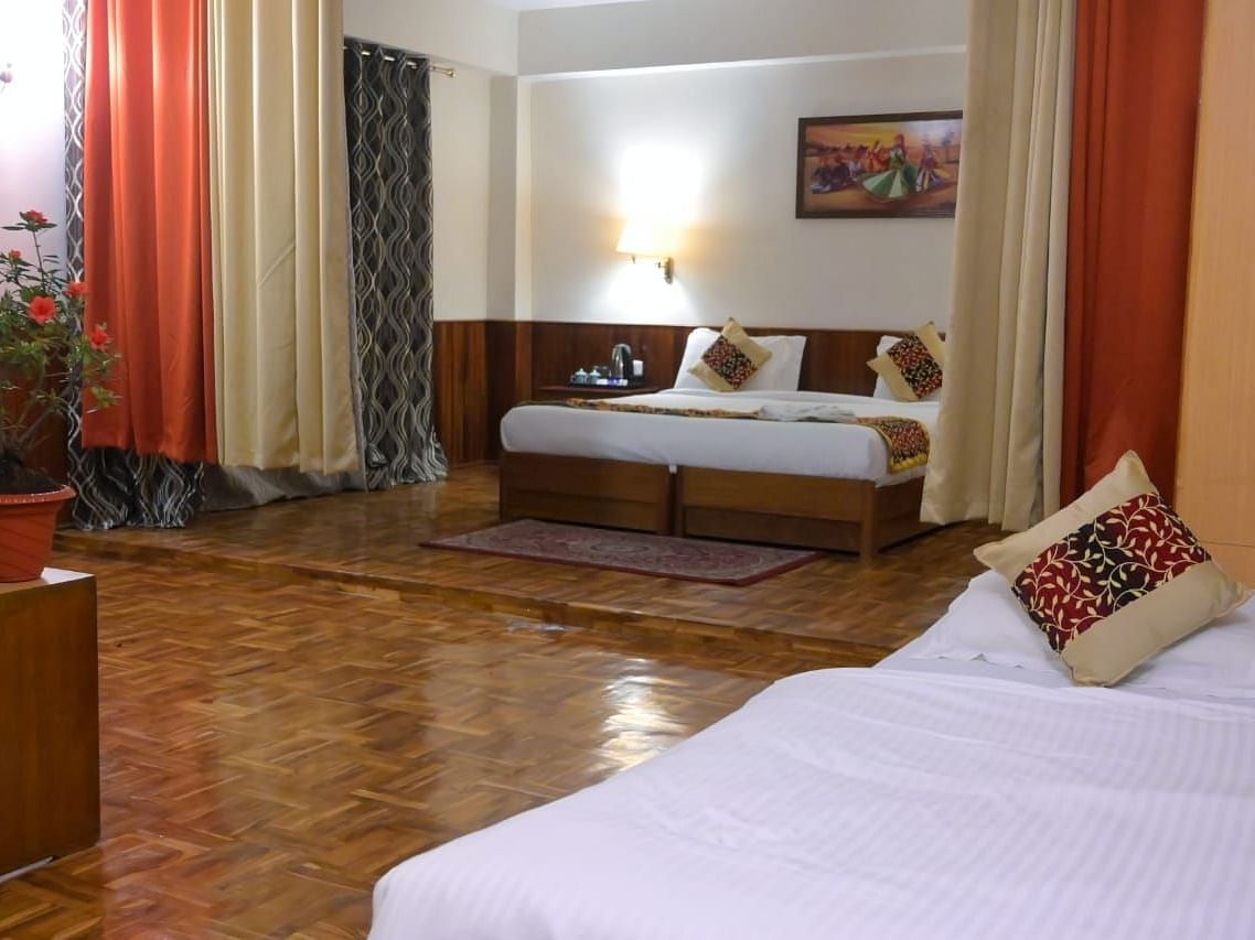 An image of the family room featuring two beds, bed side tables, indoor plants, and decorative lighting - Ecotel Chiminda, Pelling