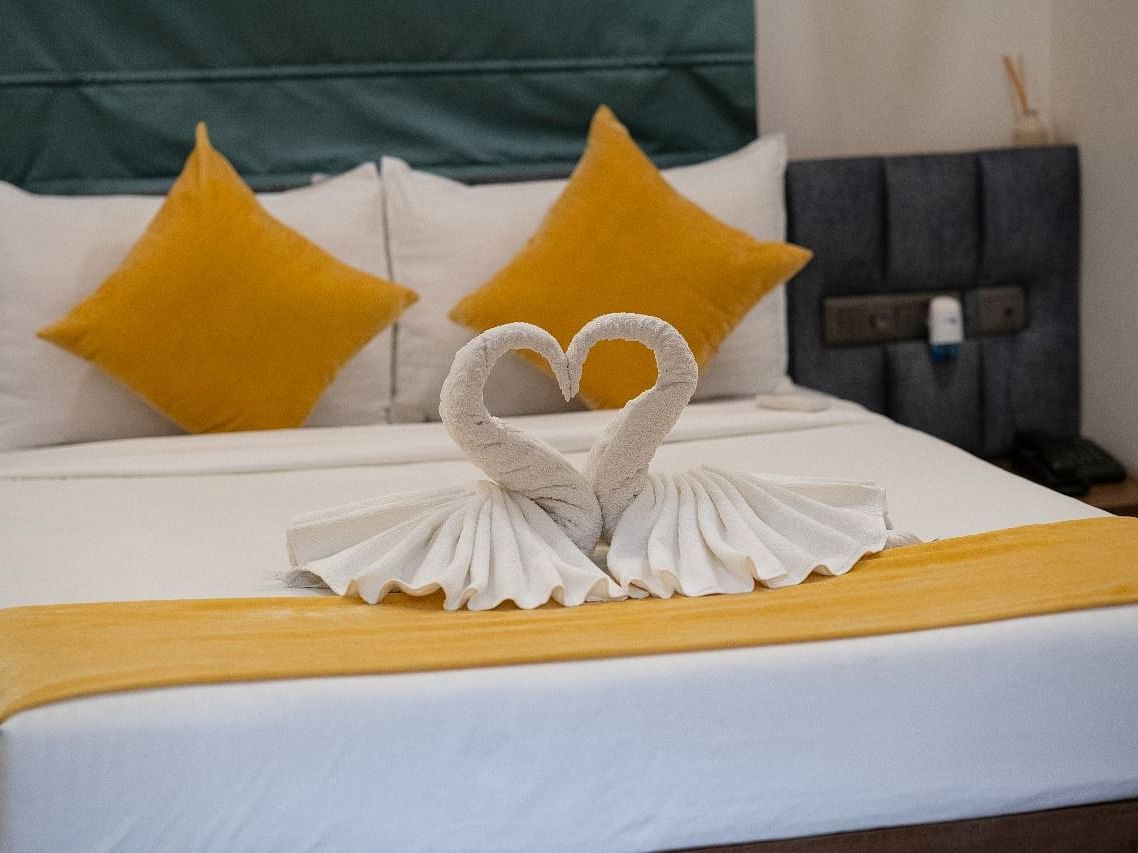 A neatly made bed with heart-shaped towels and pillows at Kyzen Smart Stays.