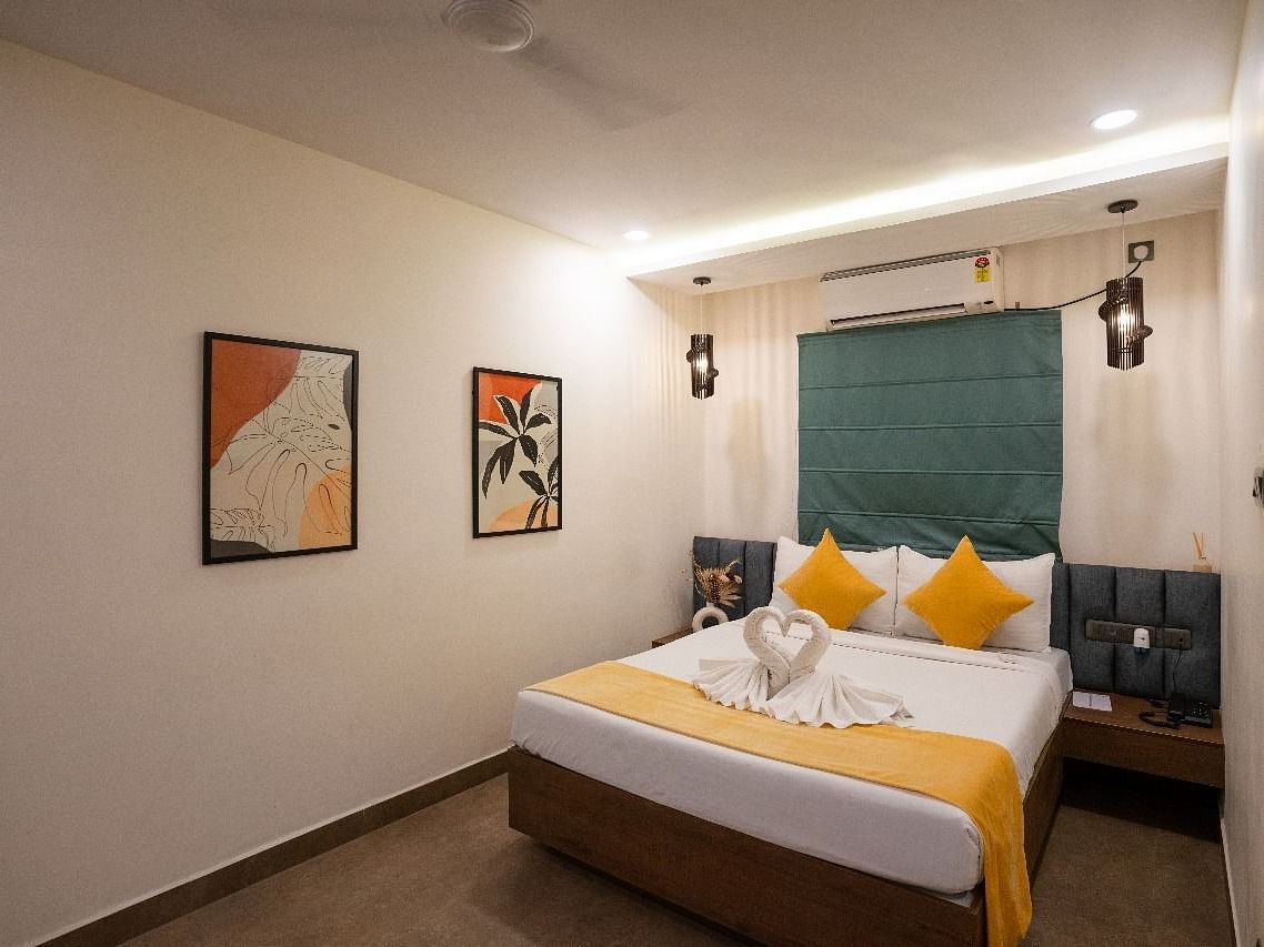 A well-lit room featuring a double bed with pillows and minimalist artwork on the walls at Kyzen Smart Stays.