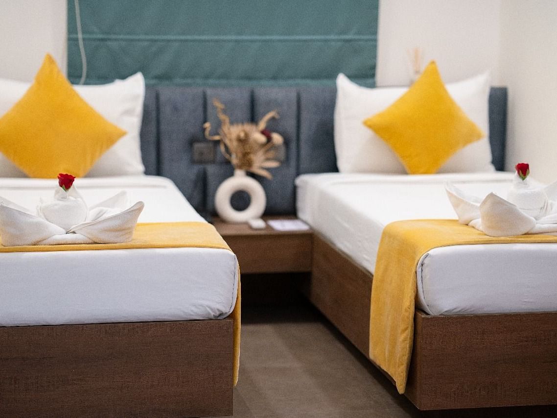 A twin room with two neatly made beds, accented with pillows and a decorative centrepiece on the bedside table at Kyzen Smart Stays.