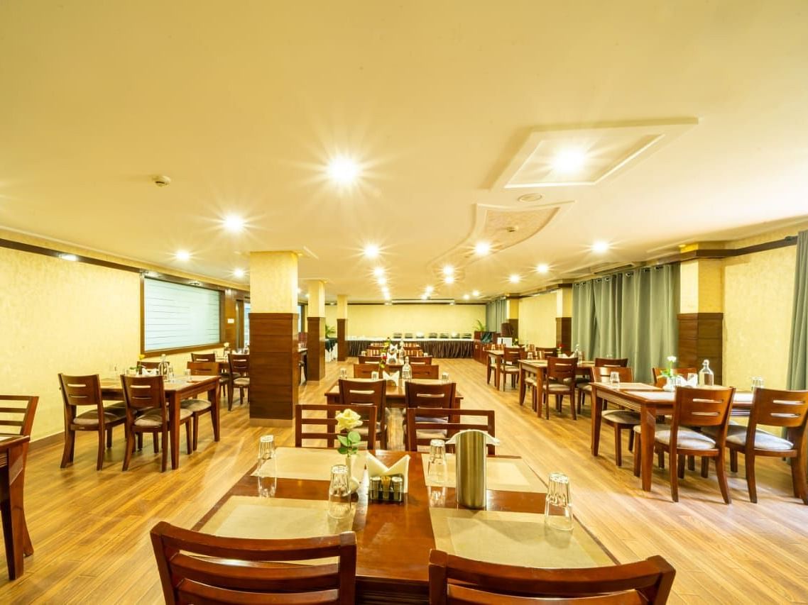 A well lit dining hall with wooden tables and chairs awaits guests, ready for meals at Lords Midtown Suites.