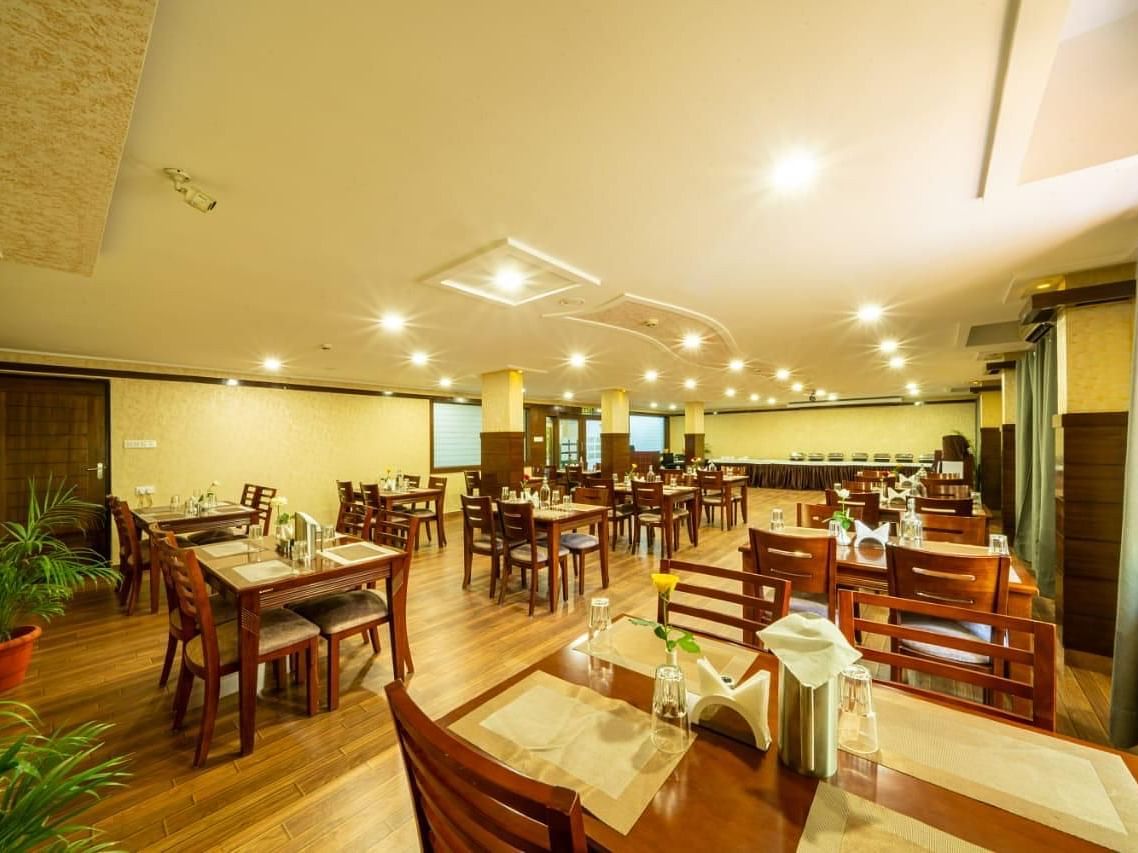 A brightly lit dining room with wooden tables and chairs offers a welcoming atmosphere for meals at Lords Midtown Suites.