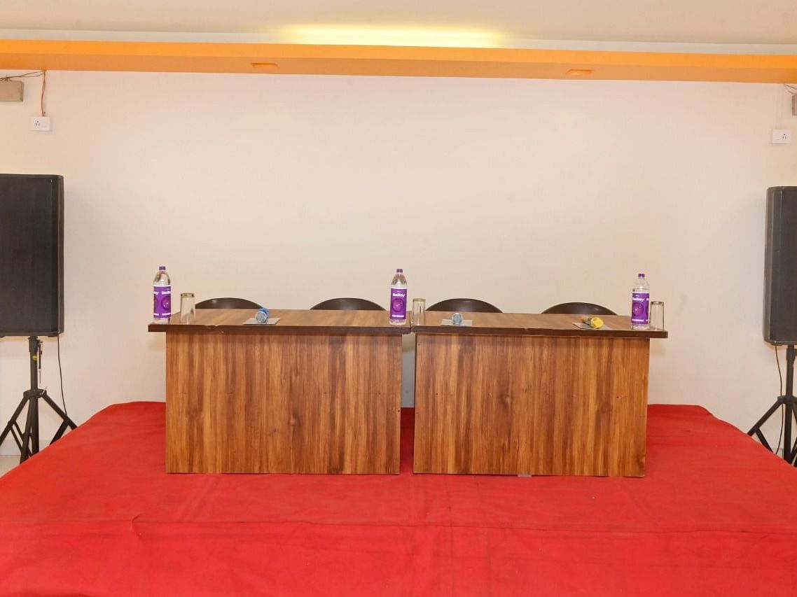 An image  of a table and chairs besides which two speakers are placed, set up in the banquet hall at Nisarga Lake Resort
