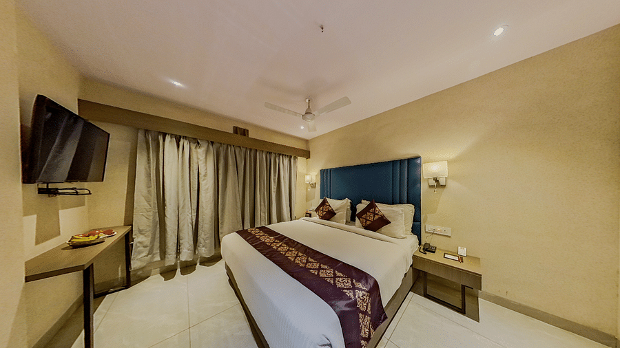 Luxurious double bed hotel room at Lords Eco Inn Dahej with blue headboard, modern amenities, flat-screen TV, and contemporary decor