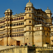 The City Palace in Udaipur, a large,  building with domes, under a bright sky. 