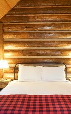 A room with a double bed and side tables with night lamps placed on it -Shaver Lake Village Hotel.