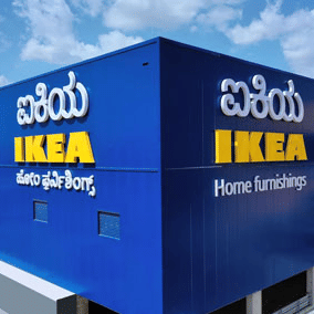 A bright facade of IKEA Bengaluru, featuring a bright blue exterior colour with the brand name written in English and Kannada language.