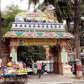 The entrance gate to the Malleshwaram Temple in Bengaluru surrounded by tall green plants.