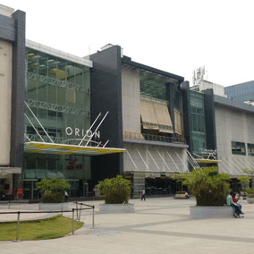 Facade of the Orion Mall in Bengaluru against an overcast sky in the background.