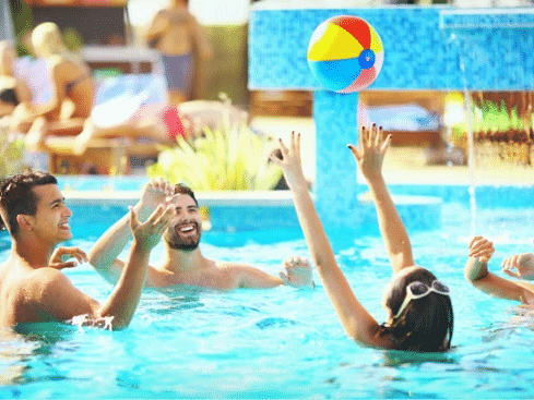 A group of friends playing together in a pool, splashing water and laughing - S Hotel Montego Bay, Jamaica.