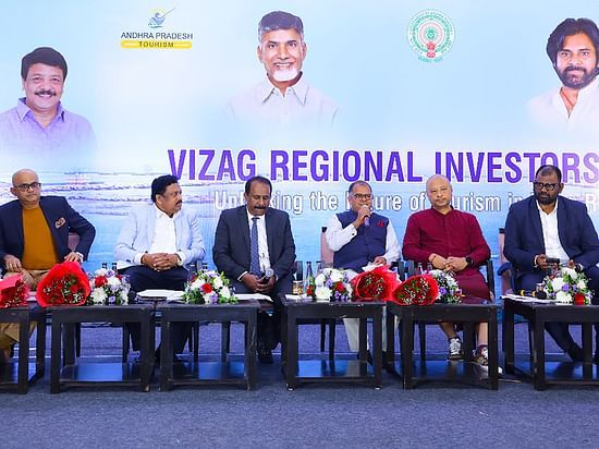 A panel of dignitaries seated on stage at the Vizag Regional Investors Meet, with a backdrop displaying Andhra Pradesh Tourism branding and images of key figures. 