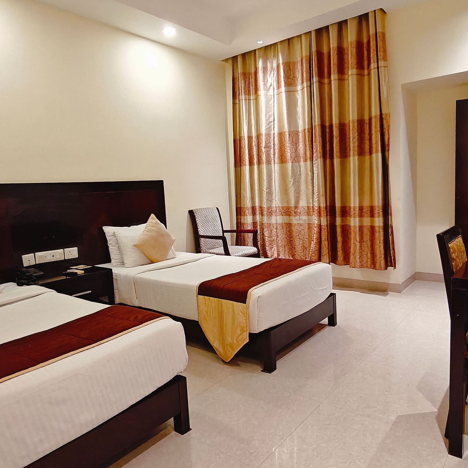 Well-lit twin-sharing guest room at Hotel Alps Residency, Krishnagiri, with modern furnishings.