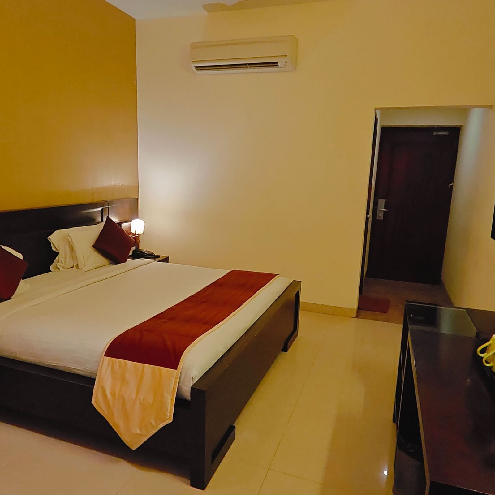 King bed room with warm lighting and functional furniture at Hotel Alps Residency, Krishnagiri.