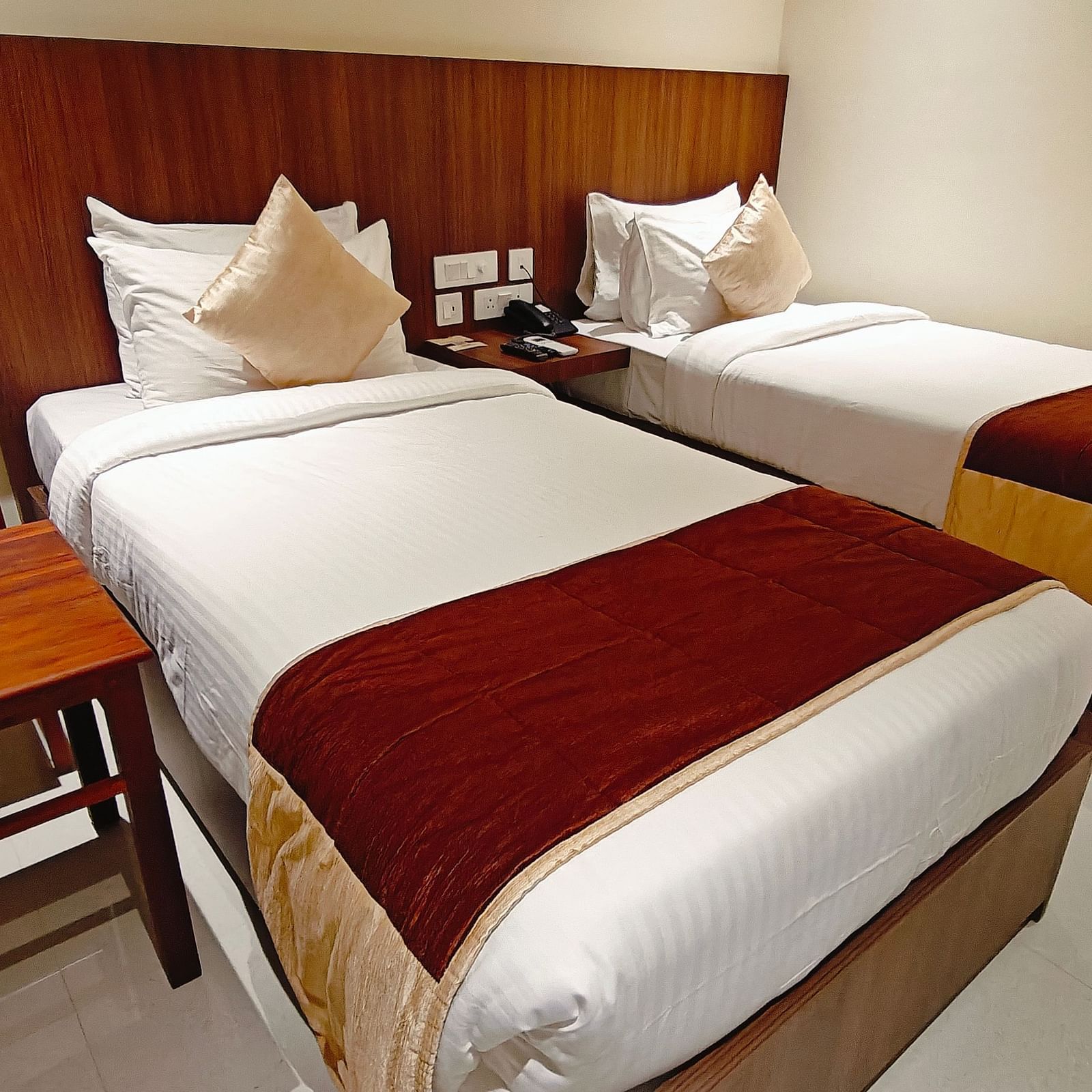 Twin-bed room at Hotel Alps Residency, Krishnagiri, with crisp white linens and warm wooden accents.