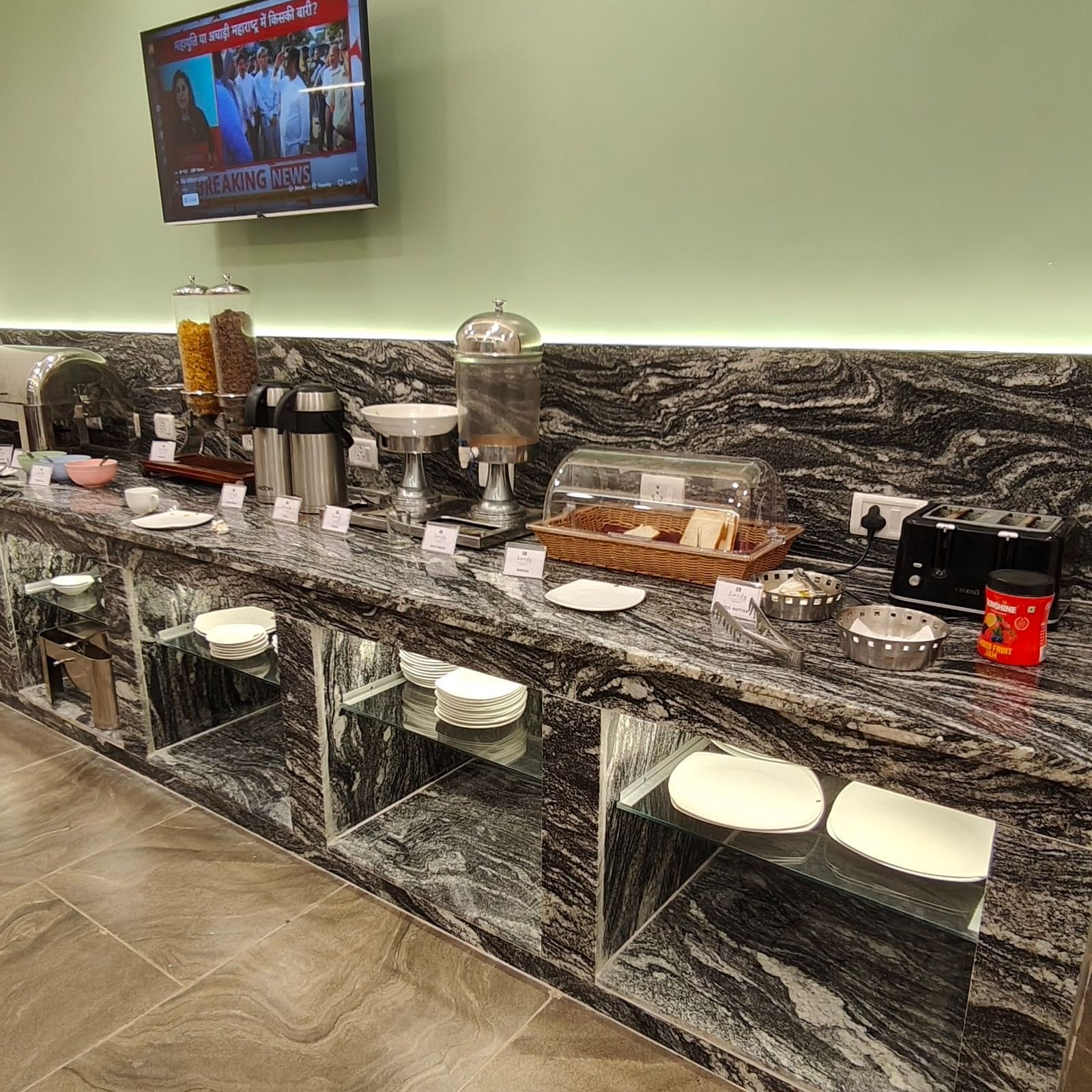 Buffet counter setup with various serving dishes and a mounted TV