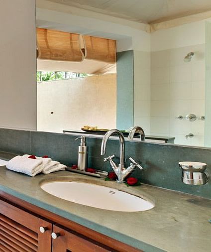 A bathroom with a sink and mirror, sliding glass doors leading to a patio, natural light - Shreyas Retreat