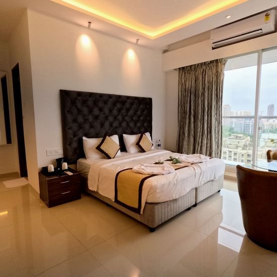 An image of the bedroom with twin beds with bedding and 2 cup-shaped arm chairs