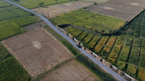 aerial view two-lane road passing through green and brown fields.